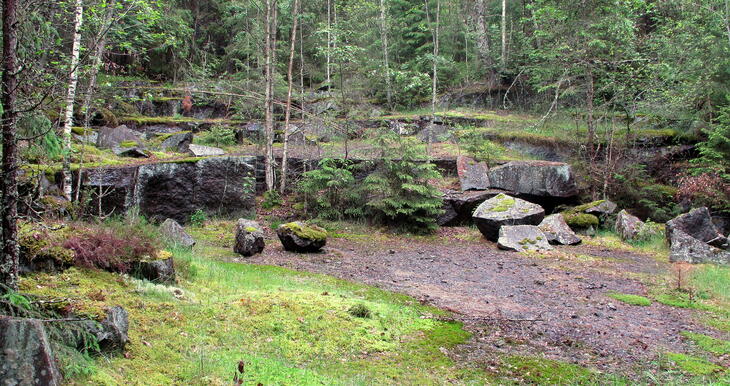 Bilde fra steinbrudd. grønn skog rundt enkelte blokker med stein