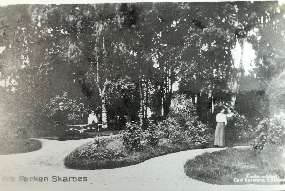 Foto fra stasjonsparken. To personer bakerst i bildet. Organiske former med grønne bed og ryddige grusganger. 