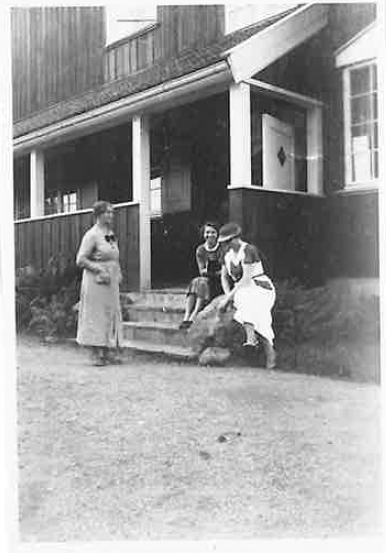 Sort-hvitt foto av søsterboligen. tre kvinner står og sitter rundt trappa