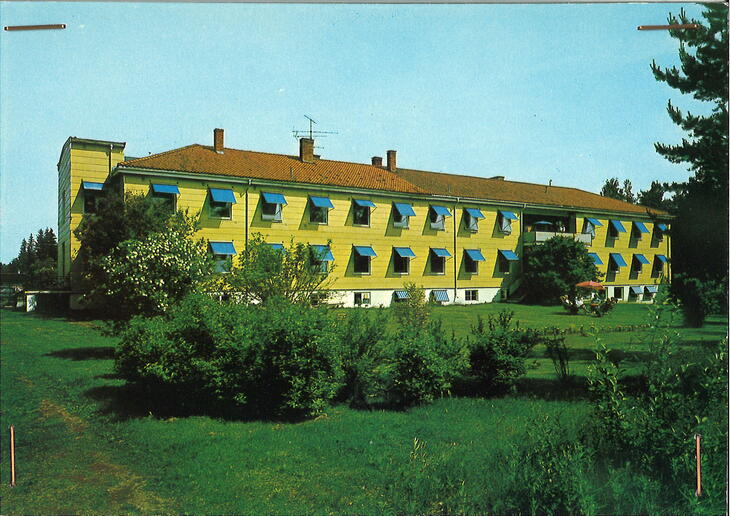 Gammelt postkort i farger med bilde av revamtismesyklehuset. Bygget er gult med blå markiser