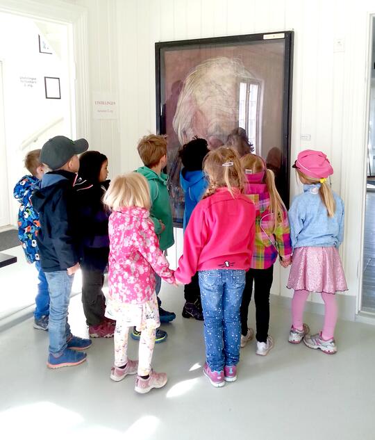 En gruppe barn studerer et portrett av Kåre Tveter