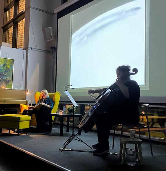 Ellen Flesjø spiller cello på scenen med et Tvetermaleri på projektor i bakgrunnen