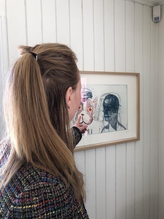 person fotografert bakfra studerer kunstverk på veggen